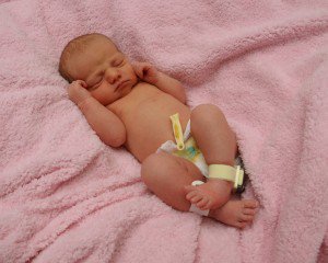 A newborn baby wearing an Accutech Cuddles tag/band